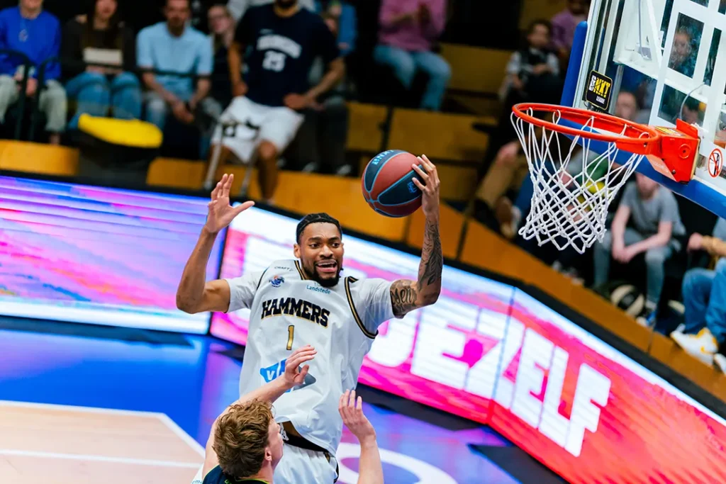 Een basketbalspeler die een lay-up maakt tijdens de wedstrijd.
