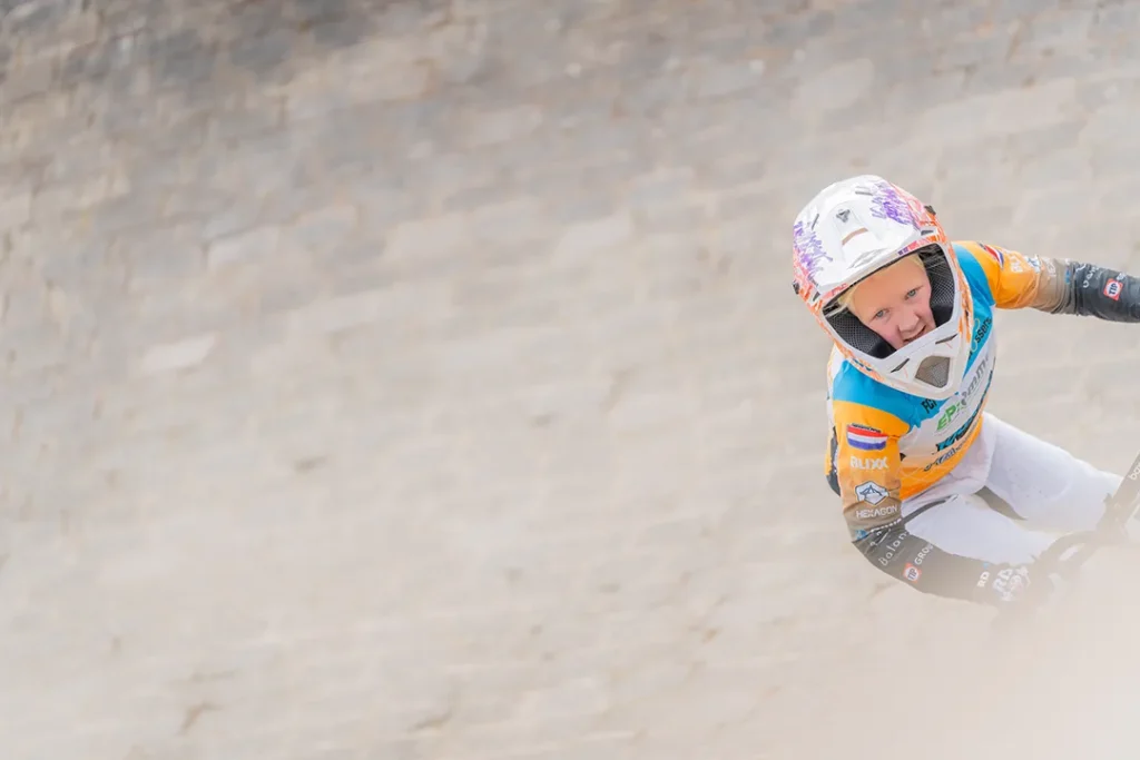 Bmx rijdster kijkt gespannen de bocht in.