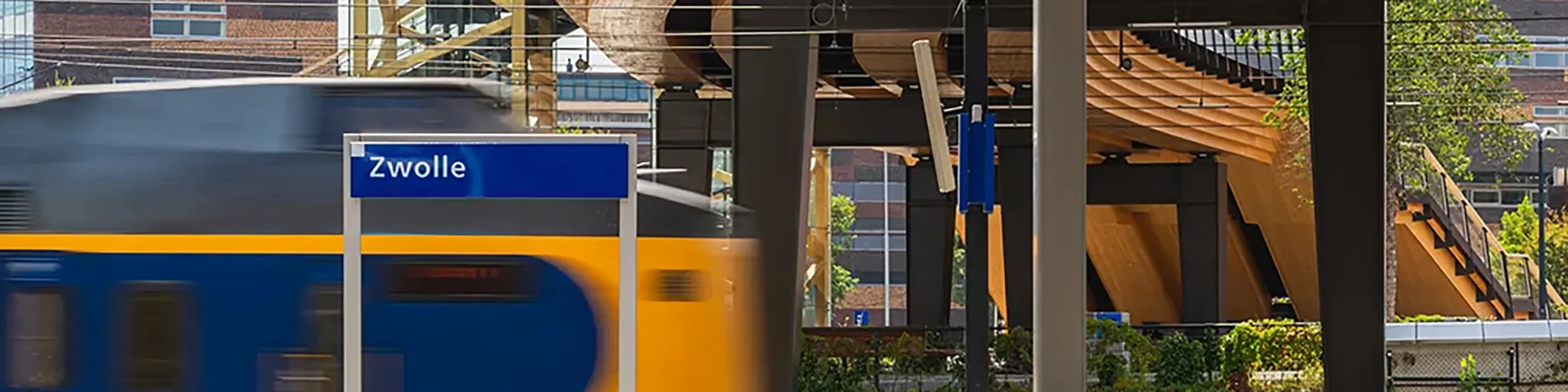 Trein van de NS rijdt onder de nieuwe Passerelle station zwolle binnen.