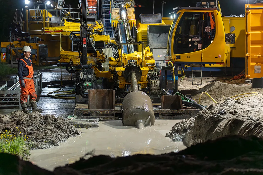 Gestuurde boring tijdens nachtwerk met boorinstallatie en medewerkers.