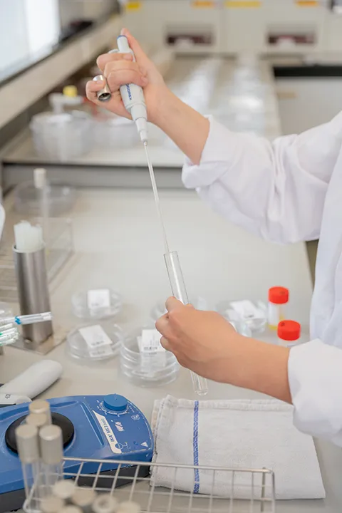 Laboratoriummedewerker pipetteert een monster tijdens kwaliteitscontrole.
