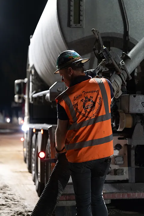 Chauffeur koppelt een betontransportwagen aan tijdens nachtwerk.