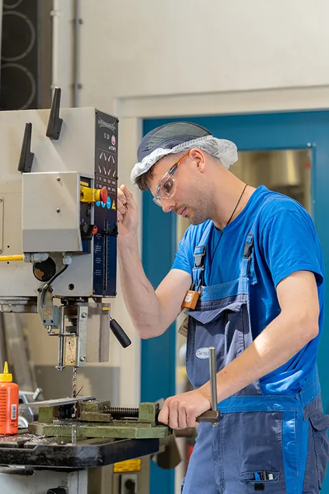 Medewerker bedient een boormachine tijdens werkzaamheden in een productiebedrijf.