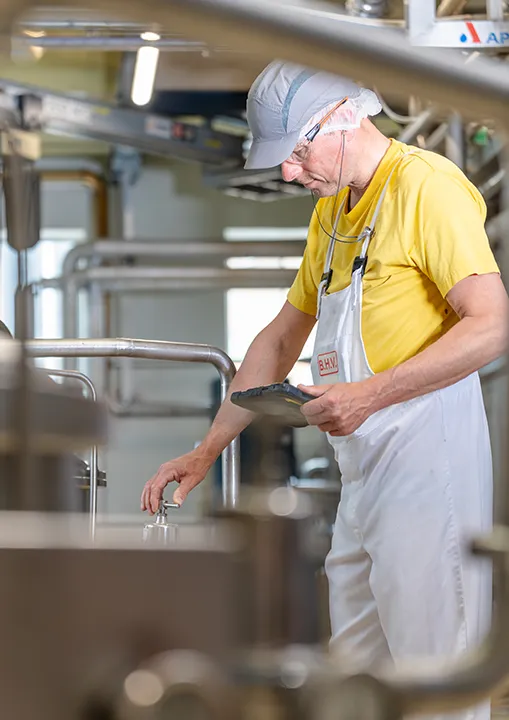 Medewerker controleert het productieproces in een zuivelfabriek tijdens een bedrijfsreportage.