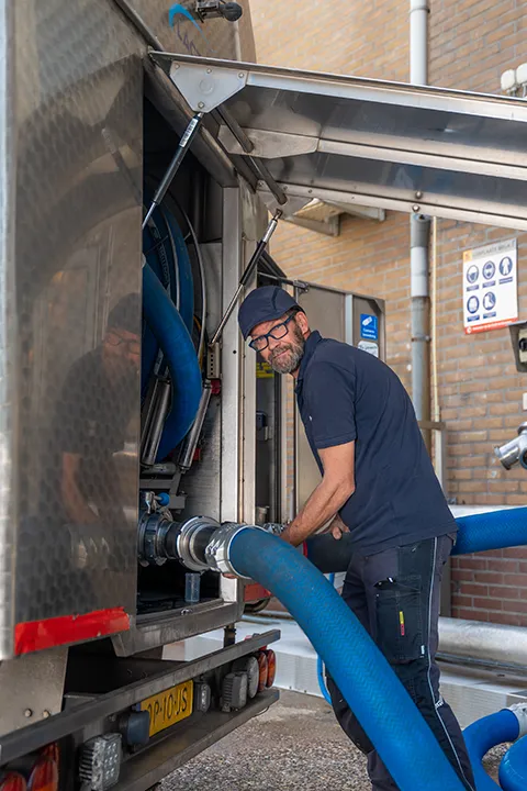 Medewerker controleert een productietank in een zuivelfabriek.
