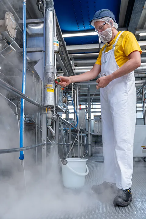 Medewerker controleert productieproces in een zuivelfabriek tijdens een bedrijfsreportage.