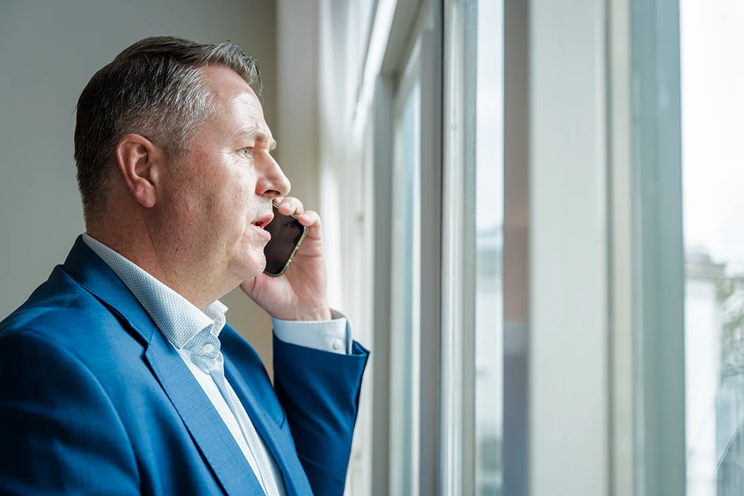 Ondernemer telefoneert bij het raam op kantoor